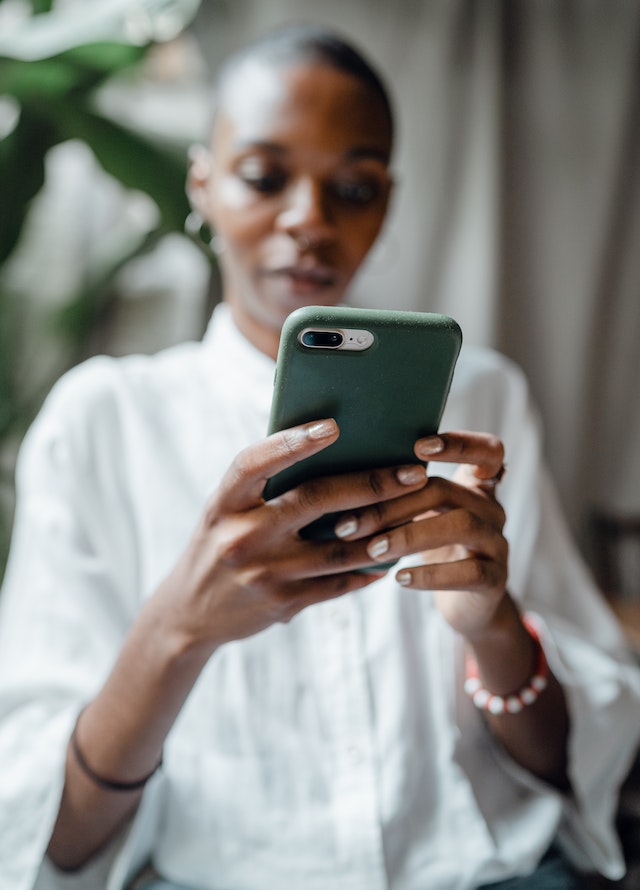 Black woman planning her move abroad on her cellphone
